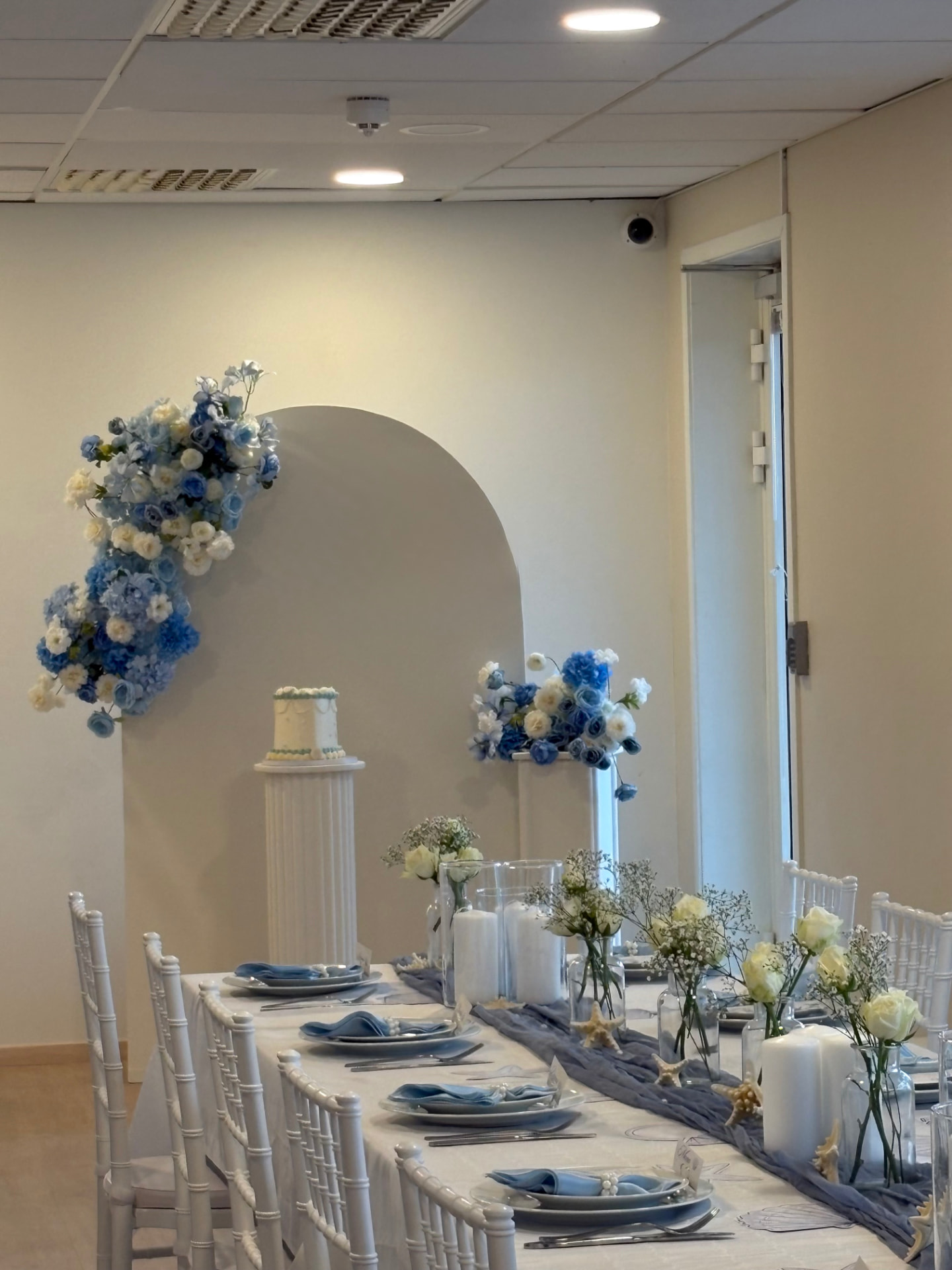 Langbord dekket med blå servietter og hvite Tiffany-stoler