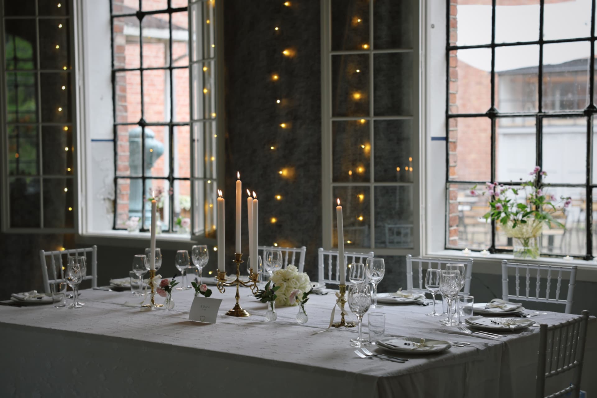 Dekket langbord med lysestaker, glass og Tiffanystoler i bryllup