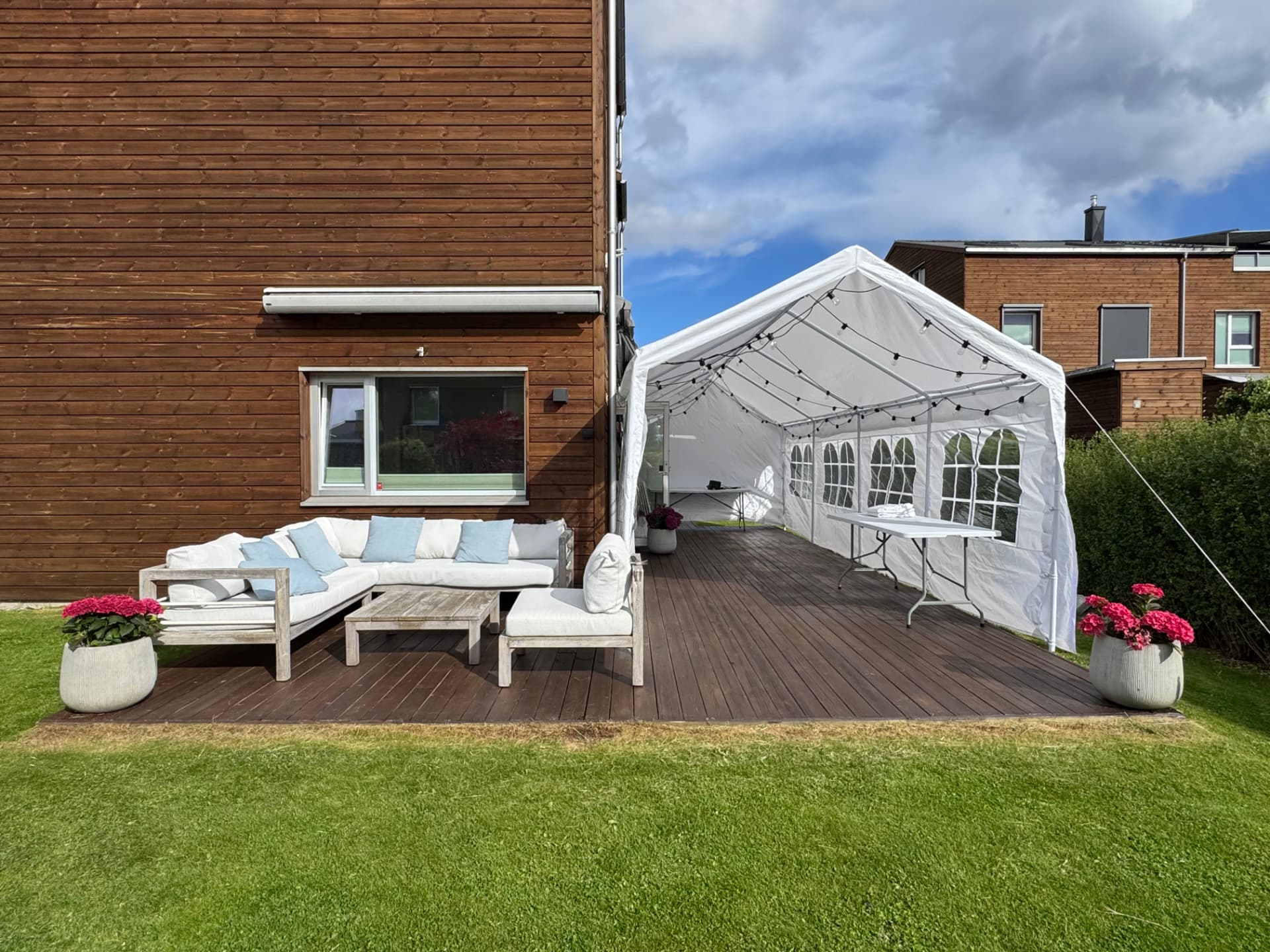 Partytelt med lyslenker og klappbord på terrasse