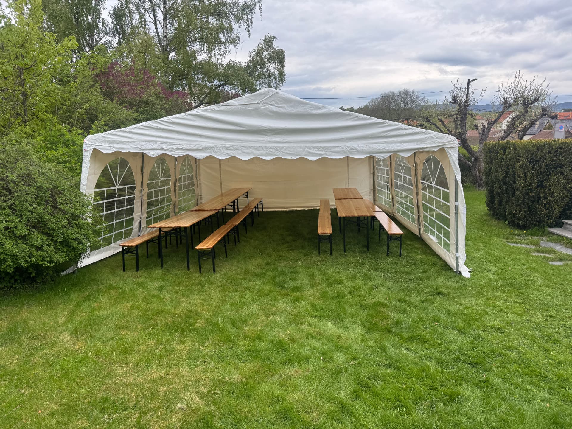 Partytelt på plenen med festivalbord og benker