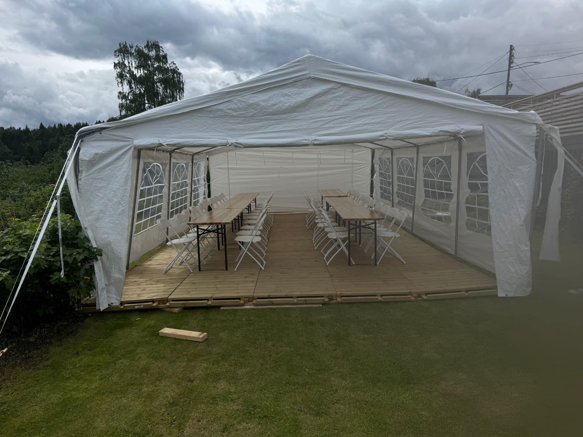 Partytelt på tregulv med langbord og hvite klappstoler
